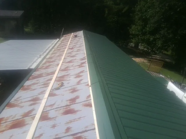 Old rusted panels beside newly installed green metal roofing — Wind Damage Roof Repair by Roofing Brothers in Belvidere